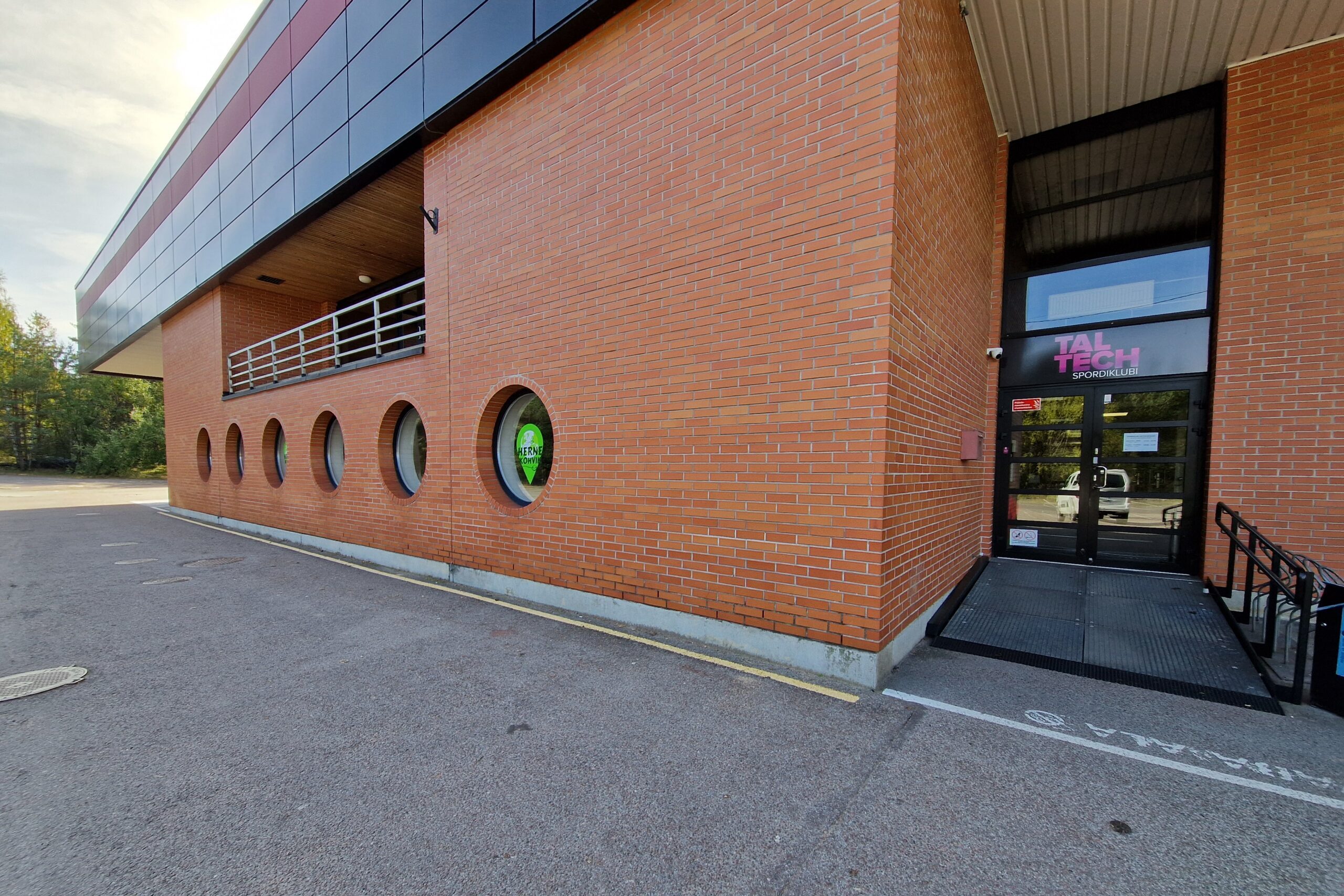 TalTech Spordiklubi peasissepääs, vasakul Herne Kohviku ringikujulised aknad